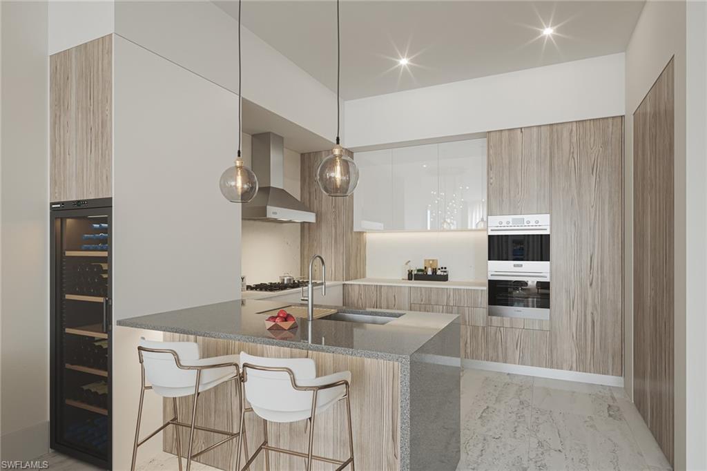Image 2: Kitchen with wall chimney range hood, a breakfast bar, white cabinetry, sink, and double oven