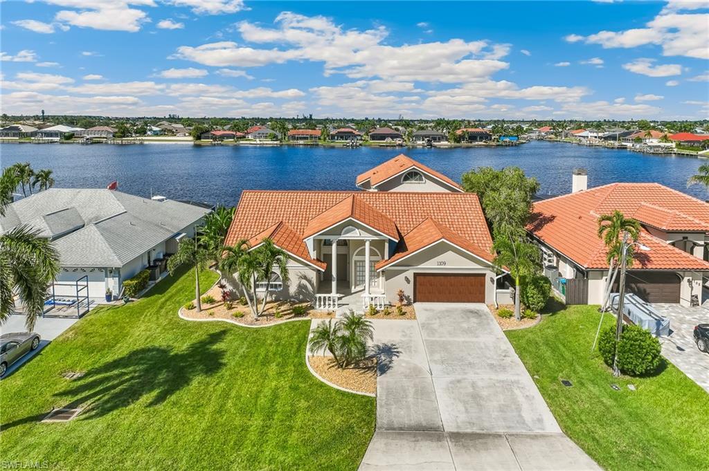 Image 1: Aerial view of residential area featuring a nearby body of water