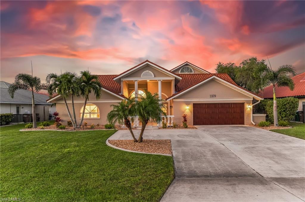 Image 4: View of front facade with a front lawn, driveway, stucco siding, and a garage