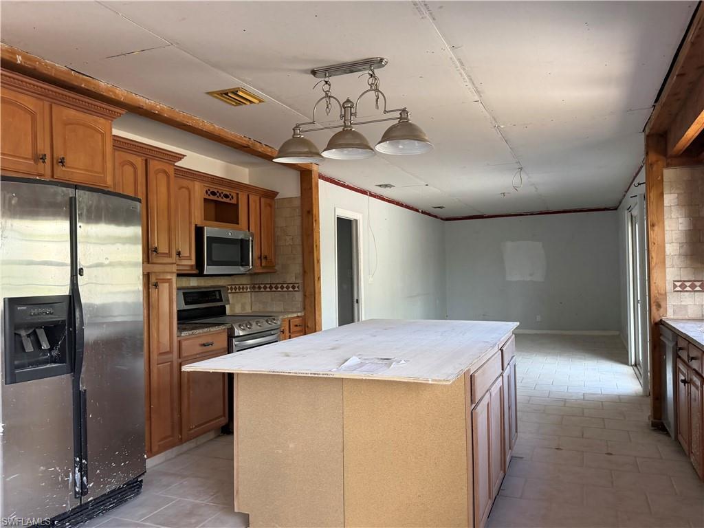Image 2: Kitchen with stainless steel appliances, a center island, wood finish cabinetry, and backsplash