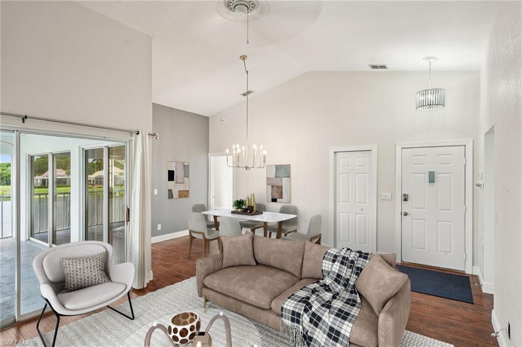 Image 3: Living area with high vaulted ceiling, a chandelier, wood finished floors, and a water view