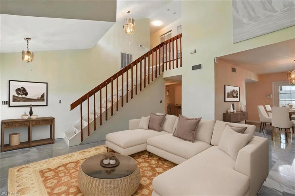 Image 3: Living room featuring a chandelier, marble finish flooring, a towering ceiling, and stairs - Virtually Stage and Edited Image