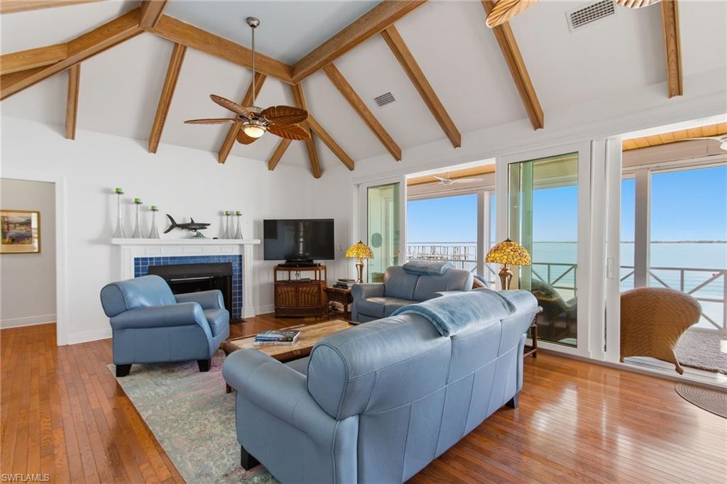 Image 4: Living room with a tiled fireplace, hardwood / wood-style flooring, high vaulted ceiling, beamed ceiling, and a ceiling fan