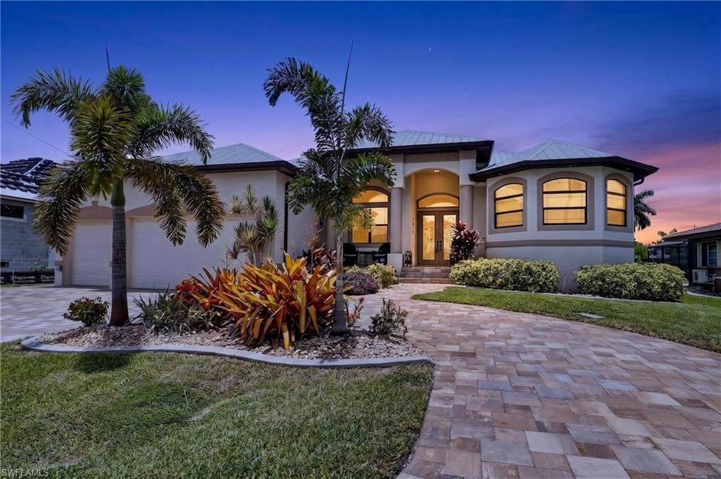 Image 2: Stucco exterior with a circle paver driveway, arched double entry doors, a multi-pane bay window, and a landscaped front yard with mature palm trees