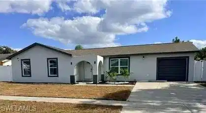 Image 3: Stucco exterior with a shingle roof, arched entryway, and an attached garage with a dark panel door