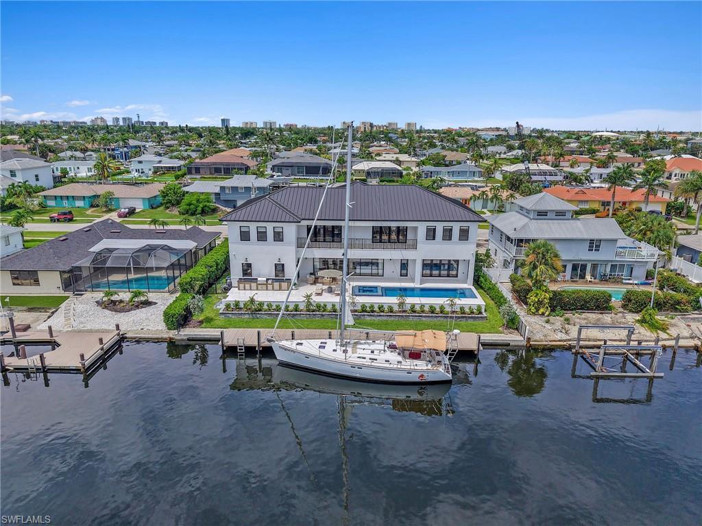 Image 3: Aerial perspective of suburban area with a pool area and a large body of water
