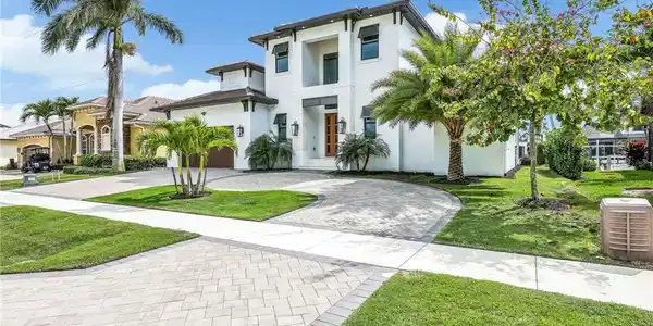 Image 2: View of front facade featuring curved driveway, stucco siding, and a front lawn