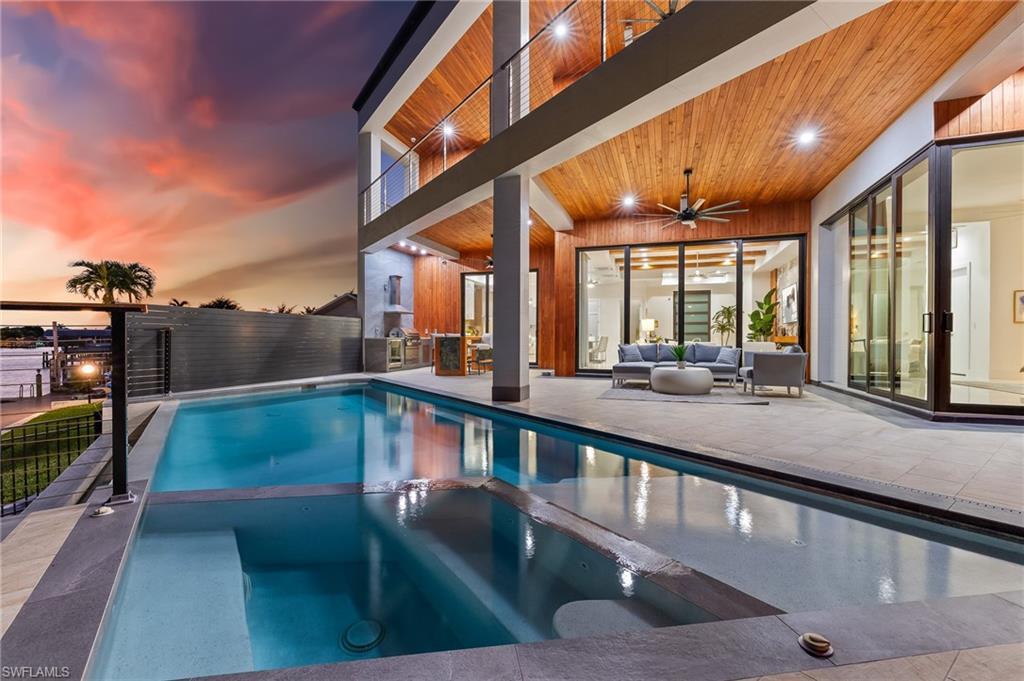 Image 1: Pool at dusk with a patio, a pool with connected hot tub, an outdoor living space, and a balcony