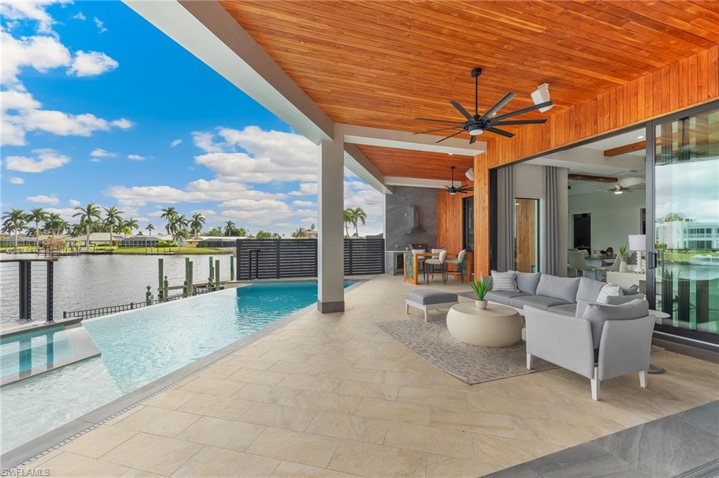 Image 3: View of pool featuring a patio, an infinity pool, an outdoor living space, and a water view