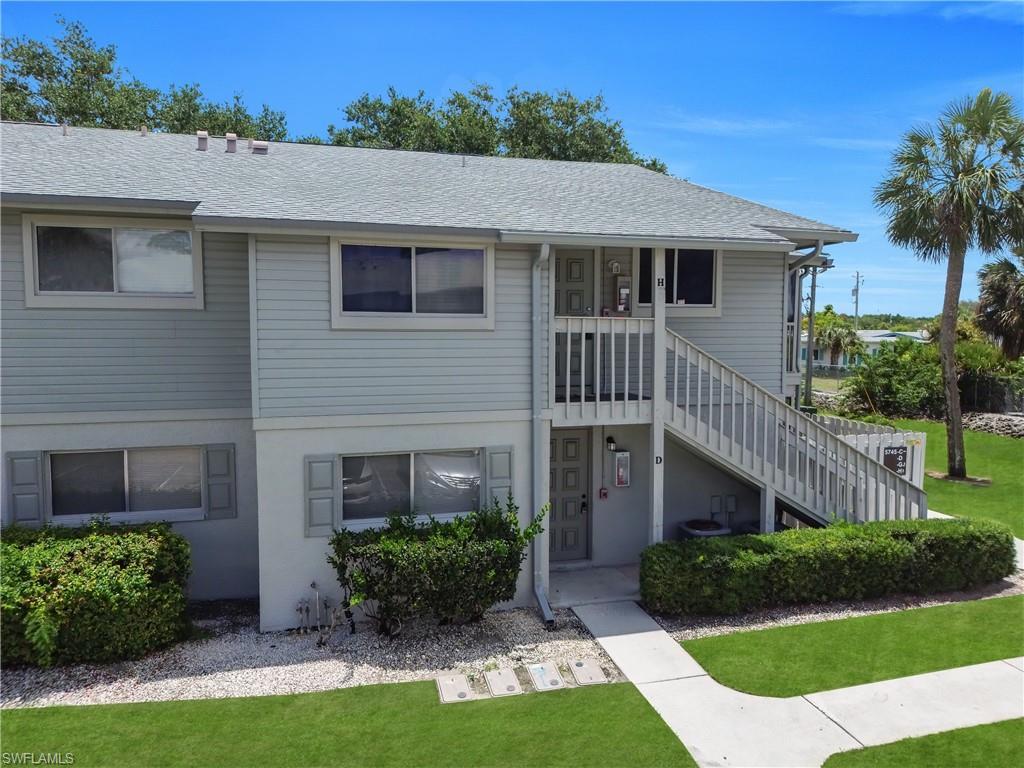 Image 2: Two-story condominium building featuring horizontal siding, a light gray shingle roof, and a prominent exterior staircase