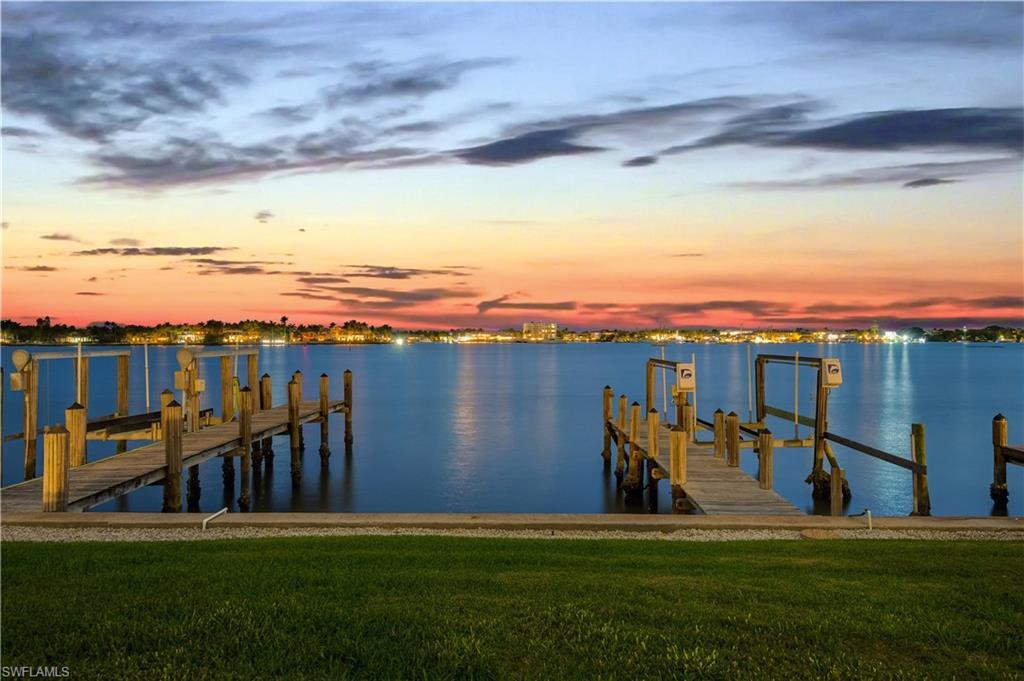 Image 3: Dock area with boat lift, a yard, and a water view
