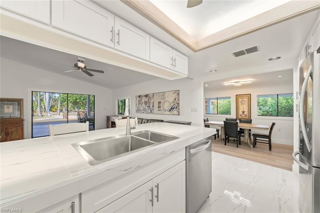 Image 3: Kitchen featuring white cabinets, a ceiling fan, healthy amount of natural light, stainless steel appliances, and lofted ceiling