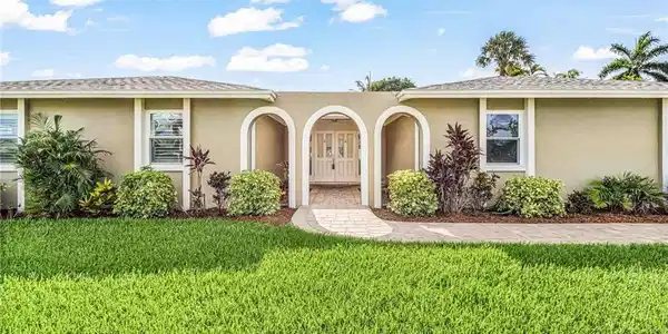 Image 4: Stucco exterior featuring an arched entryway with decorative double doors