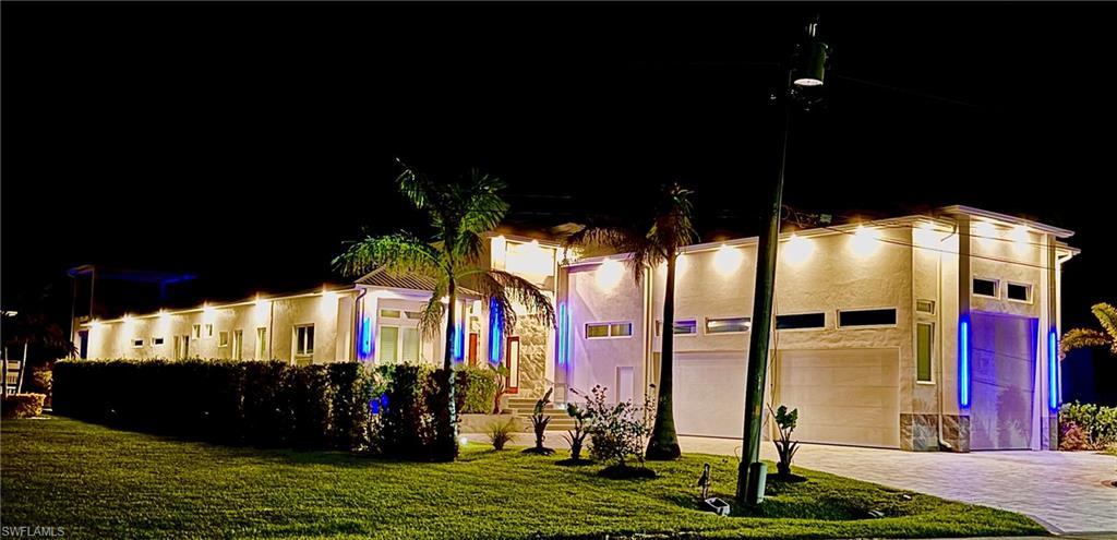 Image 2: View of front of home featuring a garage, a yard, decorative driveway, and stucco siding