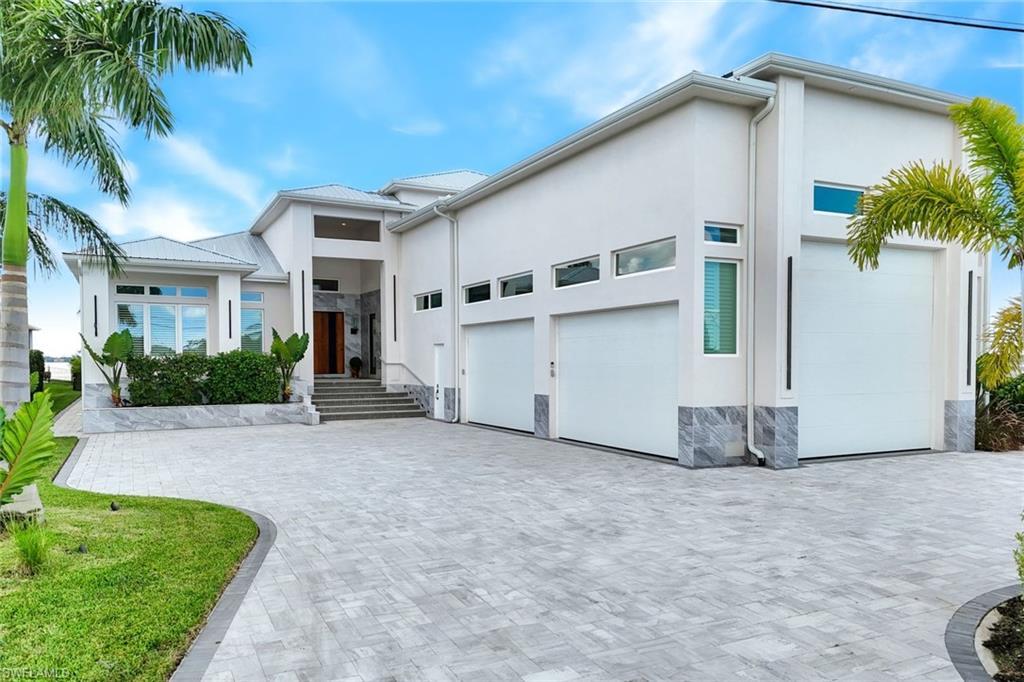 Image 3: View of front facade featuring stone siding, stucco siding, a garage, and decorative driveway