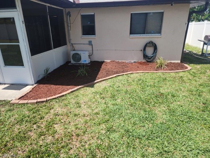 Image 3: Landscaped planting bed with decorative mulch and brick edging, complemented by a screened patio enclosure and a stucco exterior