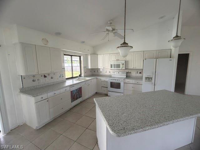 Image 3: Kitchen featuring white cabinetry, light-colored speckled countertops, a central island with matching countertop, white appliances, and ceiling fan with integrated lighting