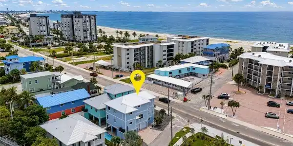 Image 2: Coastal property featuring a multi-story exterior, multiple balconies, and a paved parking area