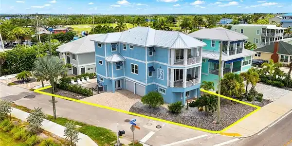 Image 4: Multi-story coastal residence featuring a metal roof, multiple balconies, and an integrated two-car garage - Virtually Edited Image