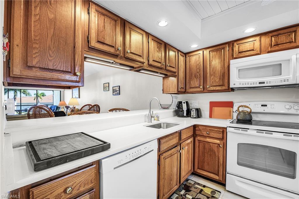 Image 3: Kitchen featuring white appliances, recessed lighting, brown cabinetry, and light countertops