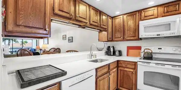 Image 3: Kitchen featuring white appliances, recessed lighting, brown cabinetry, and light countertops