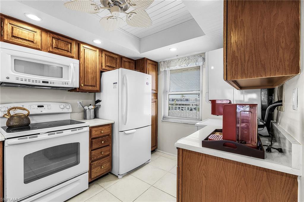 Image 4: Kitchen featuring white appliances, light countertops, light tile floors, brown cabinetry, and recessed lighting