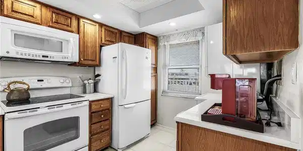 Image 4: Kitchen featuring white appliances, light countertops, light tile floors, brown cabinetry, and recessed lighting