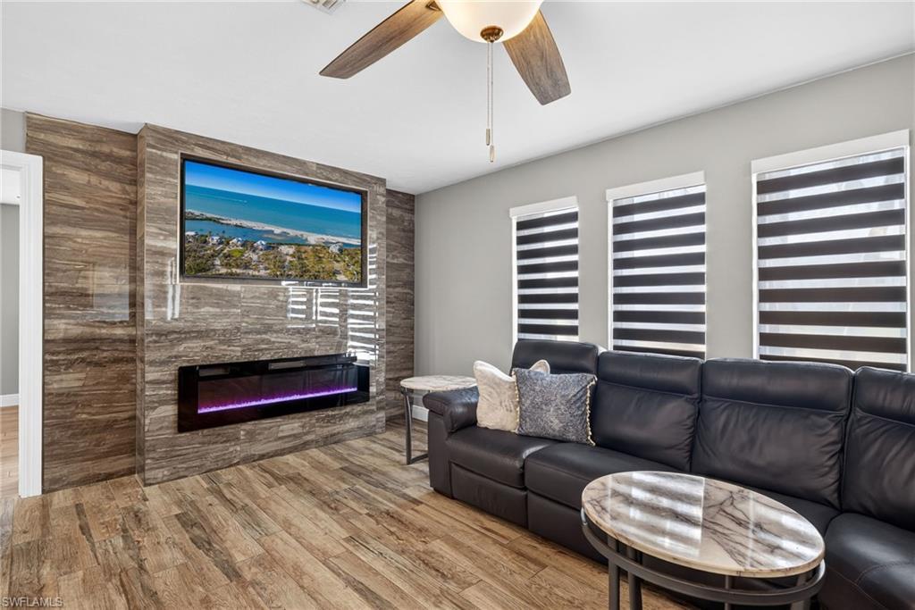 Image 4: Living area with wood finished floors, ceiling fan, and a large fireplace