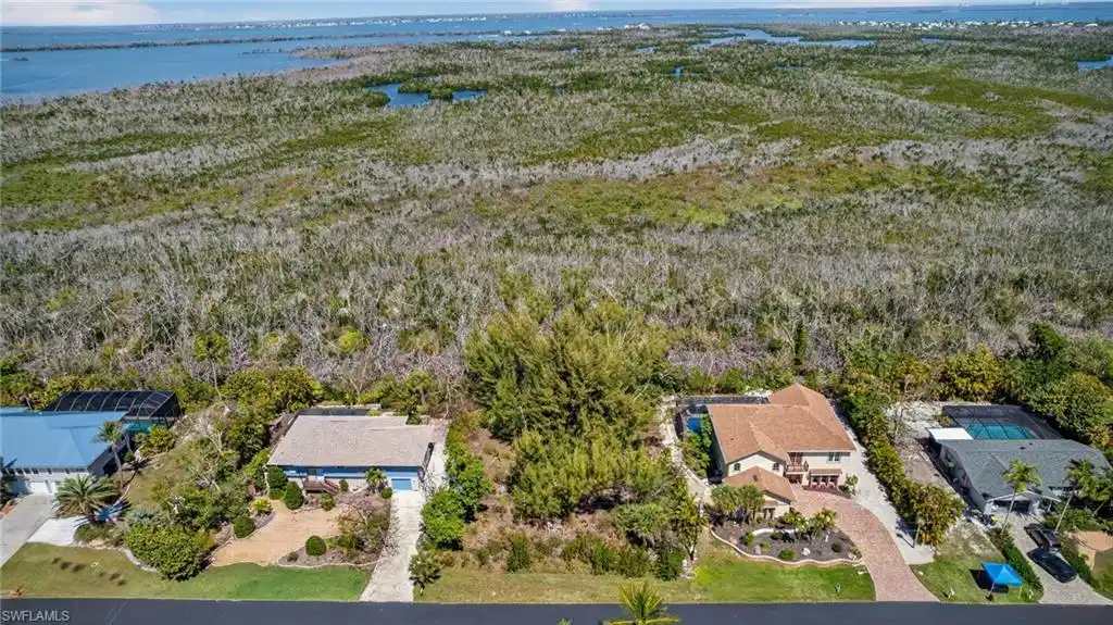 Image 1: Aerial perspective of suburban area featuring a large body of water and a forest