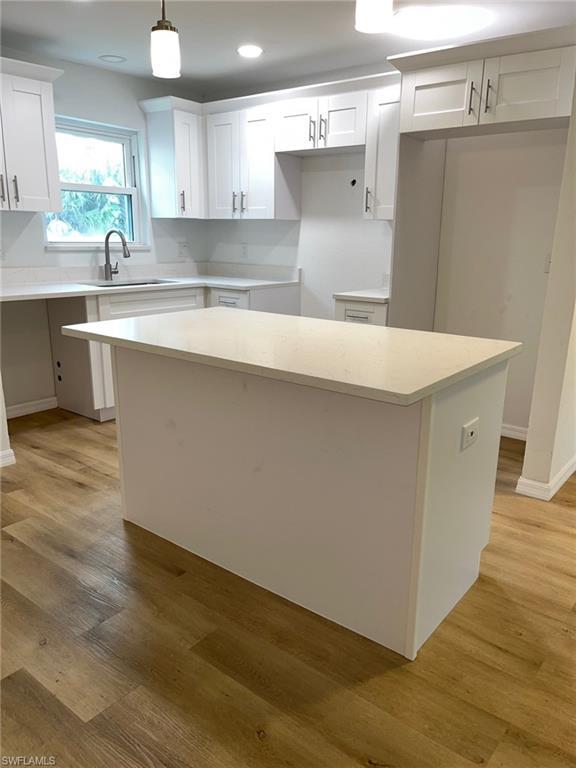 Image 1: Kitchen with a kitchen island, white cabinetry, pendant lighting, light wood-type flooring, and recessed lighting