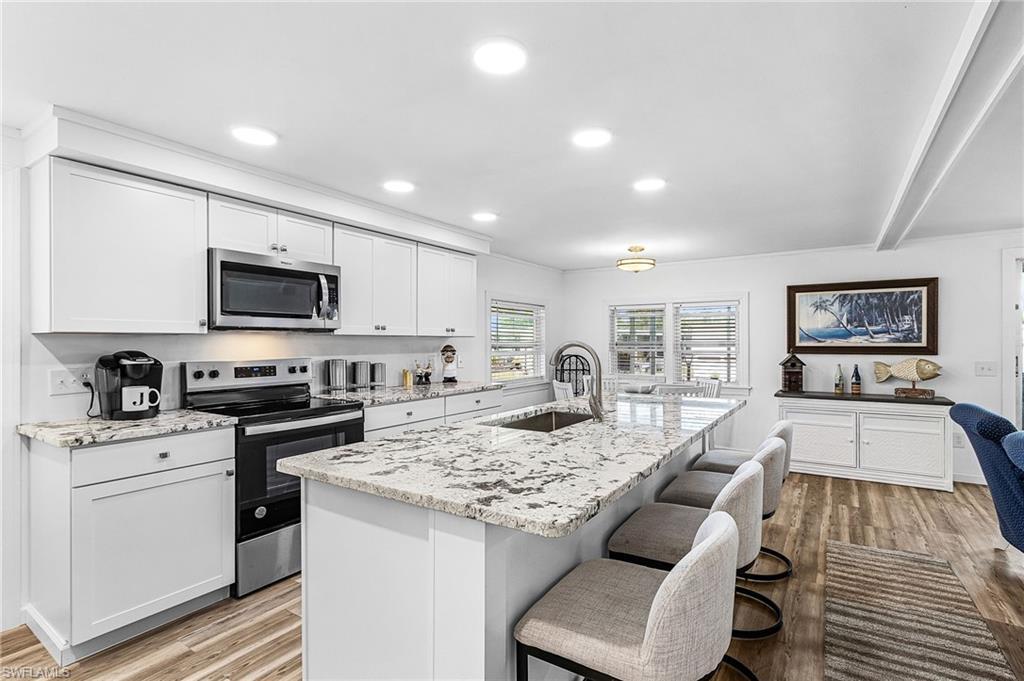 Image 1: Kitchen featuring stainless steel appliances, light stone countertops, light wood-type flooring, and recessed lighting