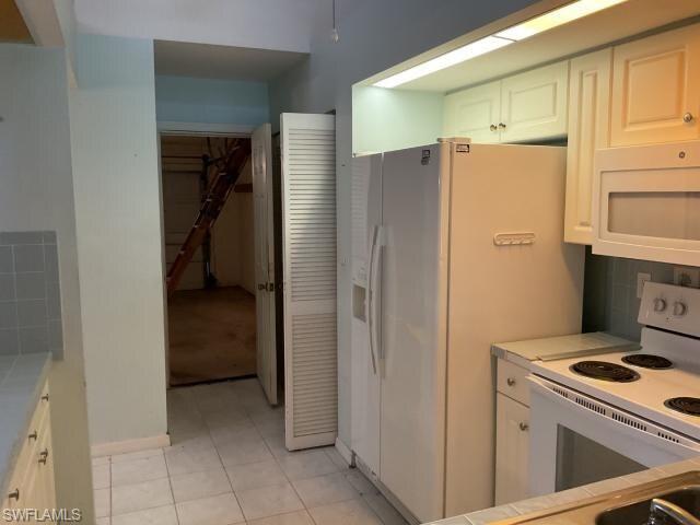 Image 4: Kitchen featuring white cabinets, white appliances, light tile patterned floors, backsplash, and tile countertops
