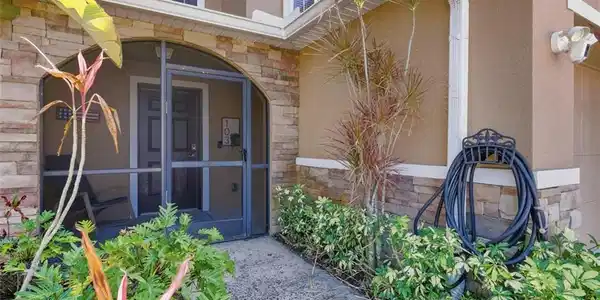 Image 2: Entrance to property with stone siding, stucco siding, and a sunroom