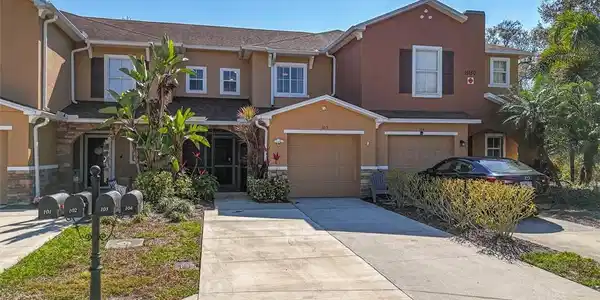 Image 3: View of front facade featuring stucco siding, concrete driveway, stone siding, and an attached garage
