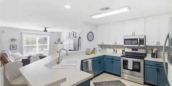 Image 4: Kitchen with dual tone cabinetry, stainless steel appliances, open floor plan, a peninsula, and backsplash