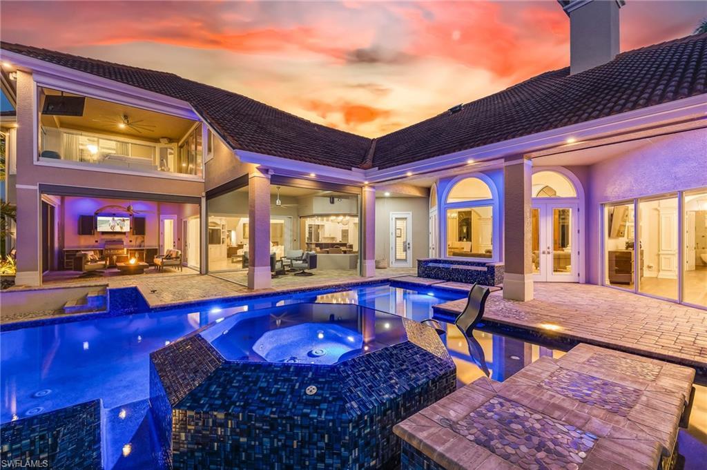 Image 3: Pool at dusk featuring an outdoor pool, an in-ground hot tub, a patio area, and outdoor lounge area