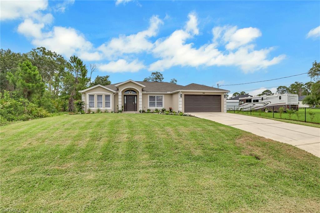 Image 2: Single-story residence featuring a stucco exterior with decorative trim, a two-car garage with a paneled door, and a concrete driveway