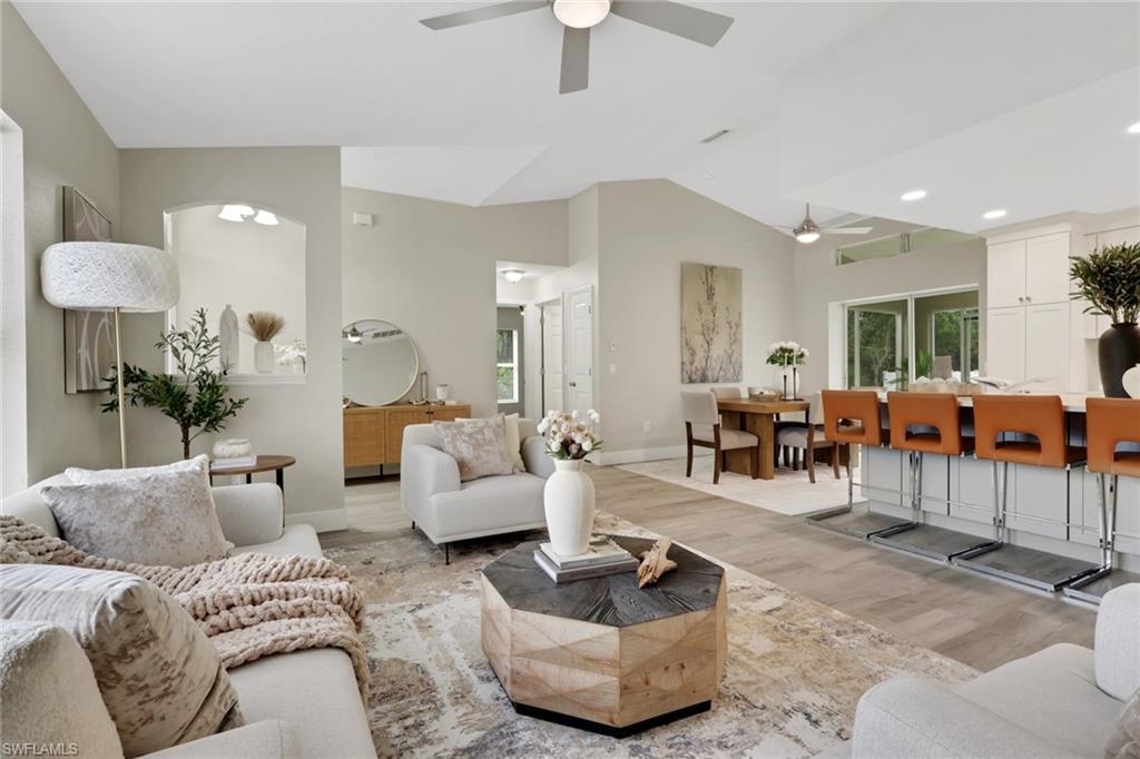 Image 3: Open-concept living area featuring vaulted ceilings, wood-finish flooring, recessed lighting, and a ceiling fan