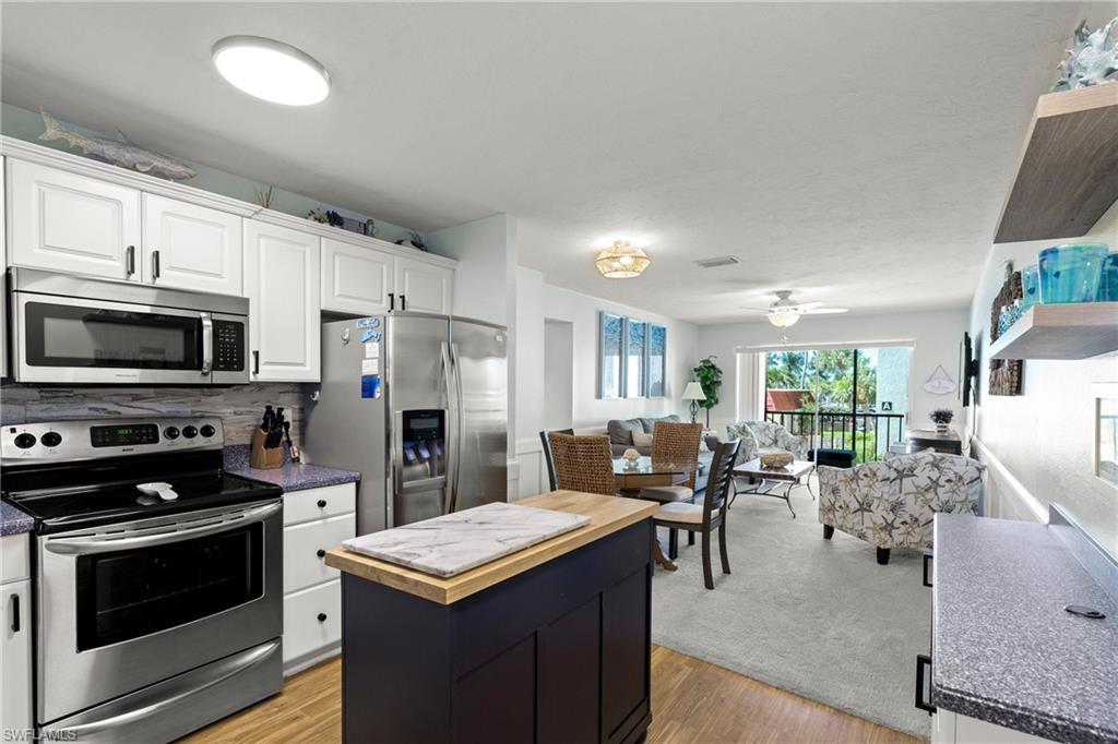Image 4: Kitchen with appliances with stainless steel finishes, a kitchen island, wooden counters, open floor plan, and white cabinetry