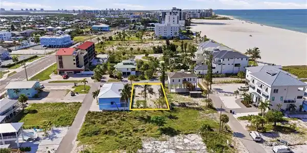 Image 4: Cleared lot with existing palm trees, positioned between developed residential structures and a paved road. virtually enhanced
