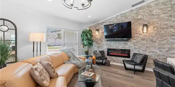 Image 3: Living room with ornamental molding, wood finished floors, lofted ceiling, a stone fireplace, and recessed lighting