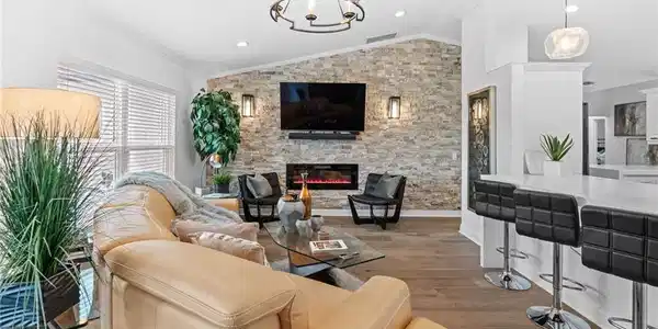 Image 4: Living room featuring wood finished floors, lofted ceiling, a fireplace, crown molding, and a chandelier