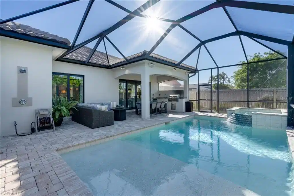Image 1: View of pool with area for grilling, a sunroom, a lanai, a patio, and a pool with connected hot tub