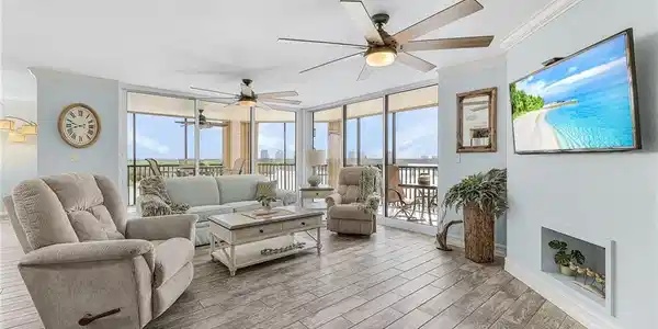 Image 2: The spacious living room has tile that looks like wood, new impact glass sliders that open to the wrap-around lanai.