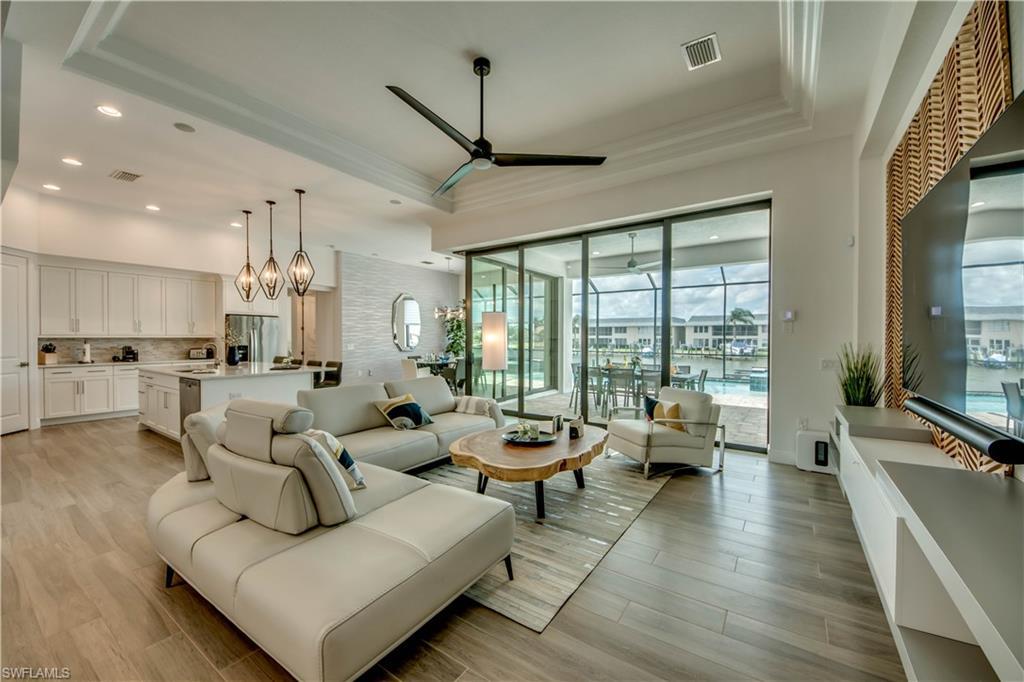Image 3: Living area with wood tiled floors, plenty of natural light, ornamental molding, and ceiling fan