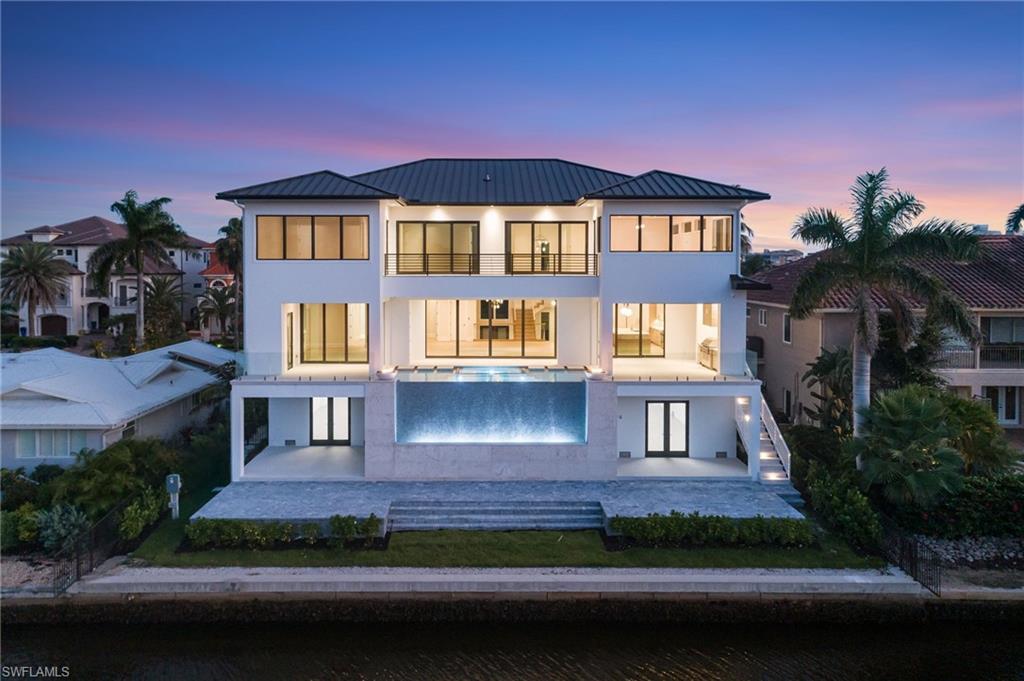 Image 2: Back of property featuring stucco siding, a balcony, a patio area, a metal roof, and a standing seam roof