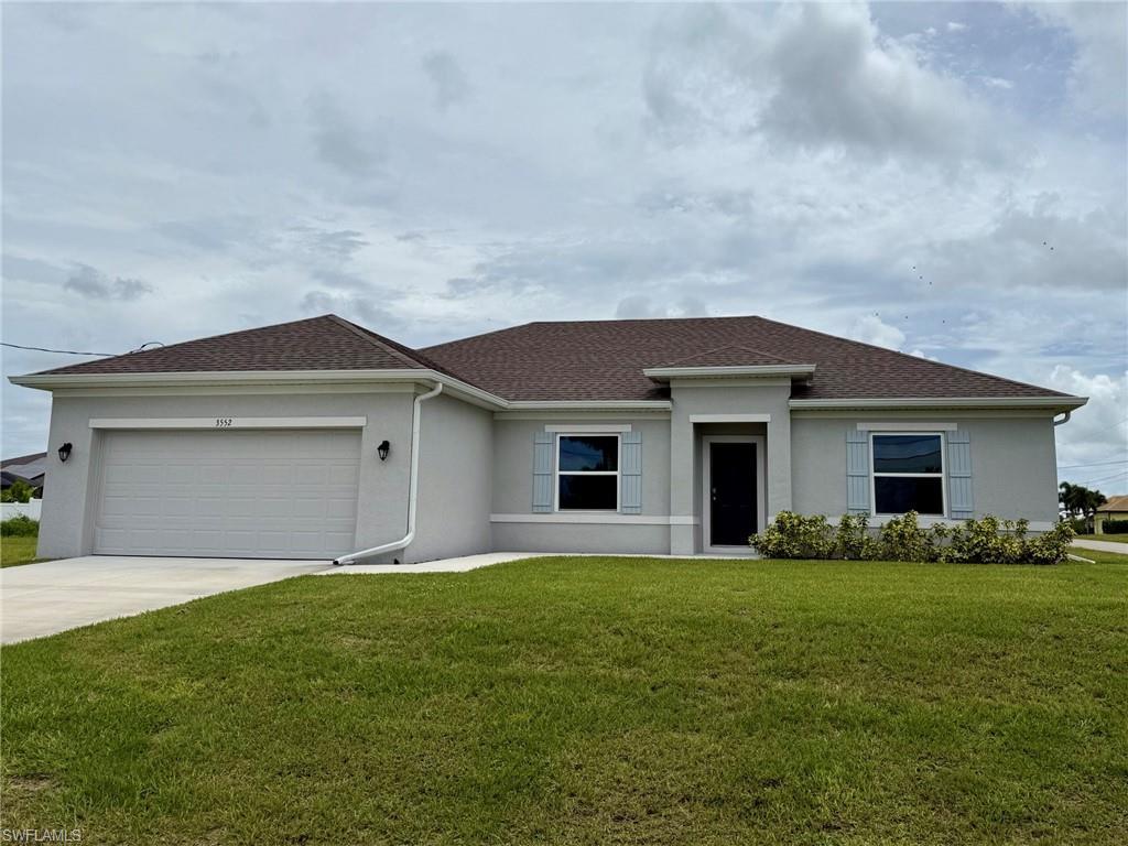 Image 1: View of front of home with stucco siding, concrete driveway, a front lawn, and an attached garage