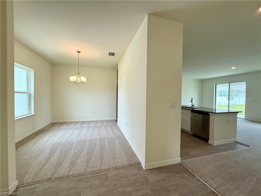 Image 3: Unfurnished dining area featuring light colored carpet and a chandelier