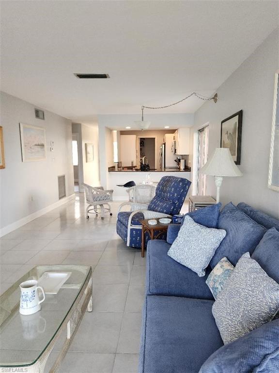 Image 1: Open-concept living area with light-toned tile flooring throughout