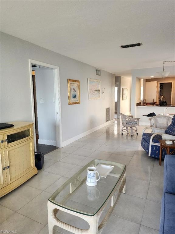 Image 2: Open-concept living area featuring light-toned tile flooring, neutral wall paint, and white trim